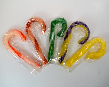 Five curved candy cane-shaped items wrapped in clear plastic, arranged in a fan shape on a plain white background. The items are translucent and come in orange-red, peach, green, purple, and yellow colorways.